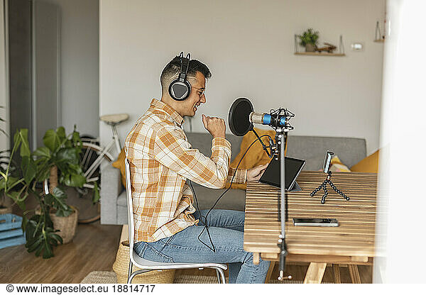 Man podcasting in front of smart phone and tablet PC sitting at home