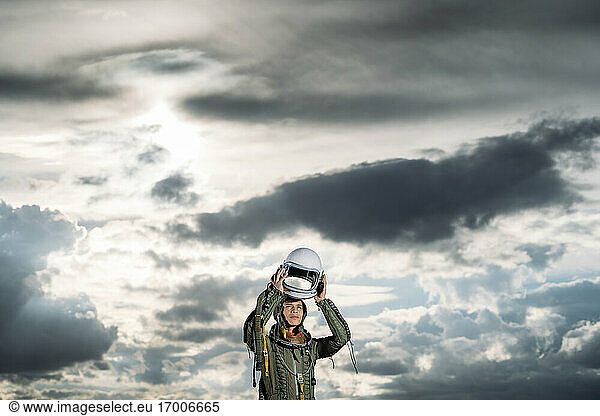 Man posing dressed as an astronaut on a meadow with dramatic clouds in the background