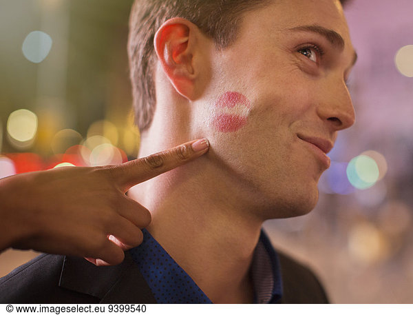 Man posing with lipstick print on cheek in city