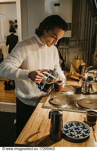 Man pouring coffee in cup at home