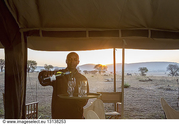 Man pouring drinks in drinking glasses at Serengeti National Park