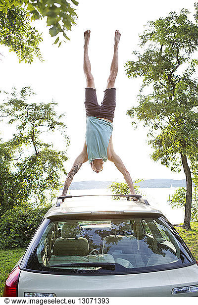 Man practicing hand stand on car