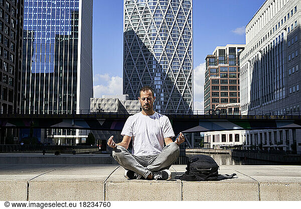 Man practicing meditation in front of building