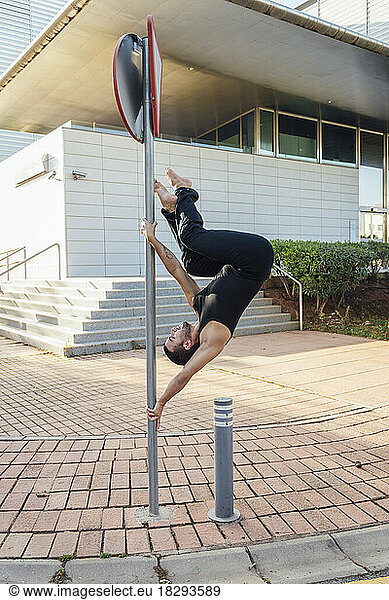 Man practicing pole dance outside building