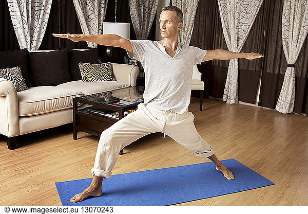 Man practicing warrior 2 yoga positing at home