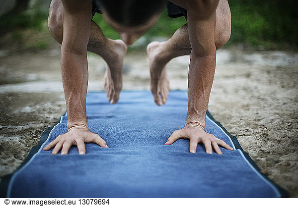 Man practicing yoga in crow pose on exercise mat