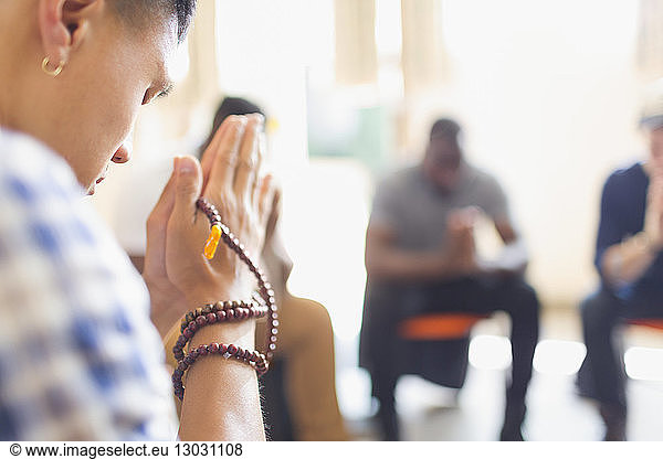 Man praying with prayer beads in prayer group