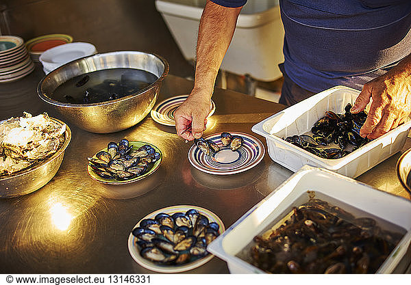 Man preparing and arranging fresh mussels