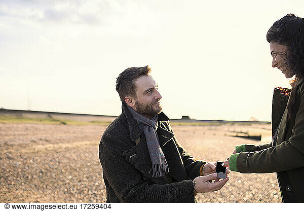 Man proposing to girlfriend on sunny winter beach