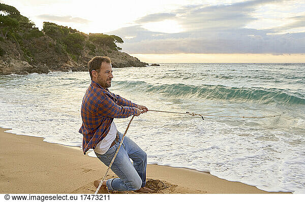 Man pulling rope from sea at beach