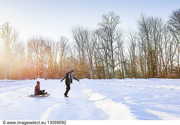 Man pulling woman sitting on sledge