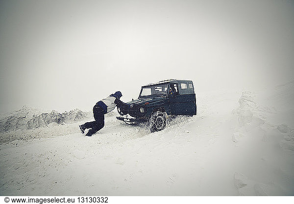 Man pushing car on snow field
