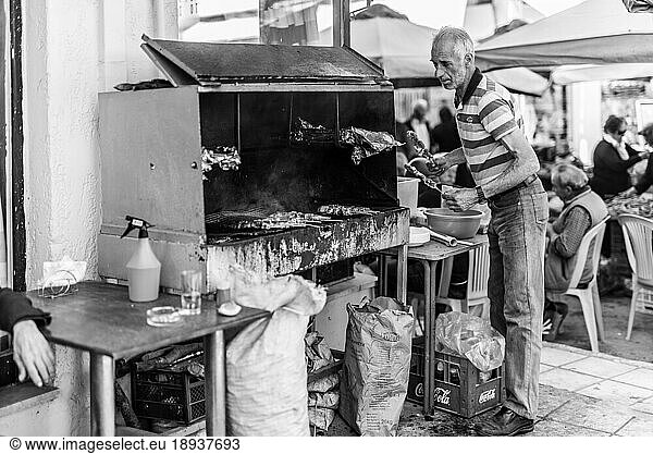 Man put Souvlaki on a charcoal barbecue in the village Tymbaki in south-central Crete. Saturday is Farmers market in the village  All folks  workmate  farmer comes to the market and the tavernas  have Souvlaki  beer or vine