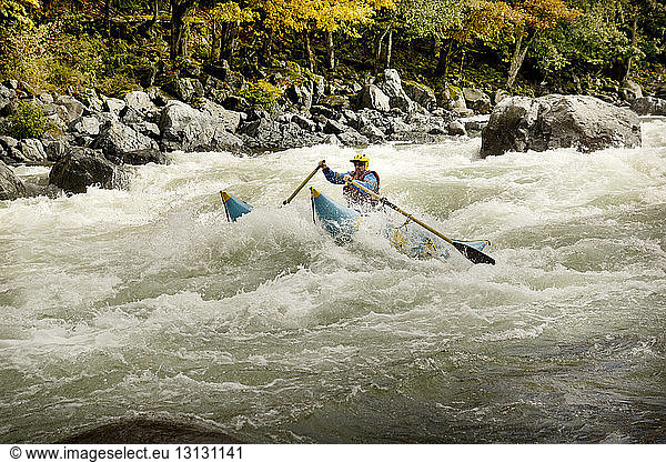 Man rafting in river against forest