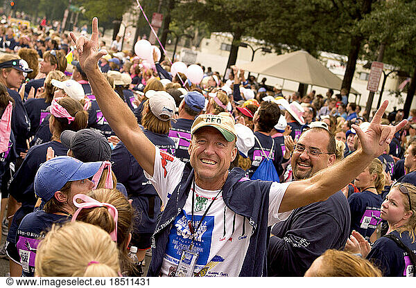 Man raises his arms at the close of a 60 mile breast cancer walk in Washington DC.