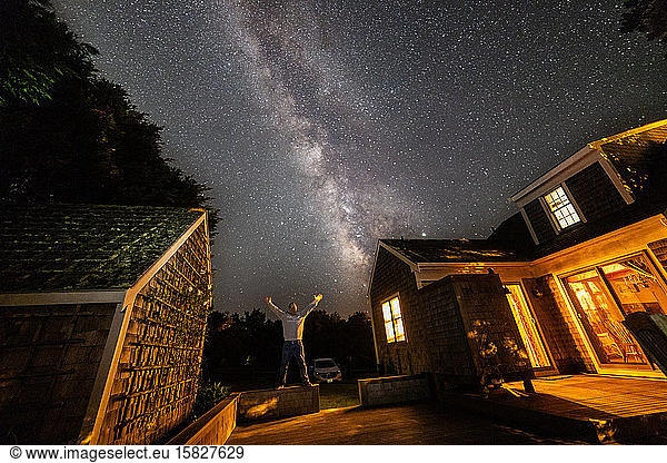Man raising arms under Milky Way galaxy on Nantucket.