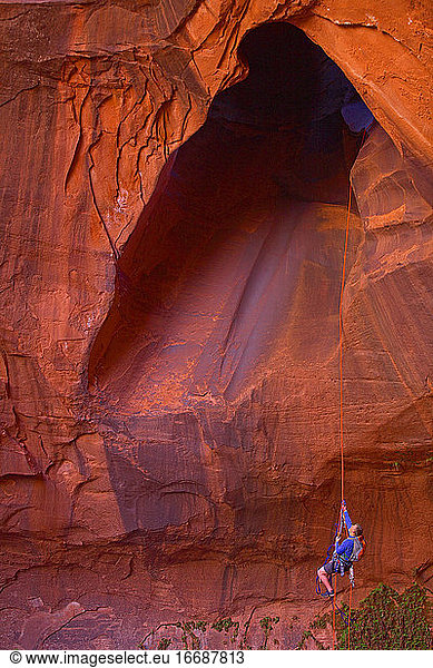 man rappelling into cave at Escalante's giant staircase