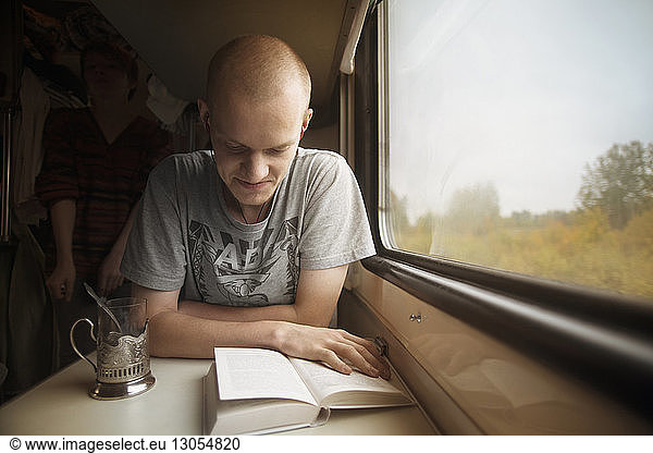 Man reading book while travelling in train