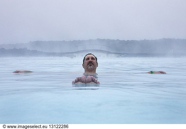 Man relaxing in Blue Lagoon against sky