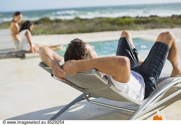 Man relaxing in lounge chair at poolside