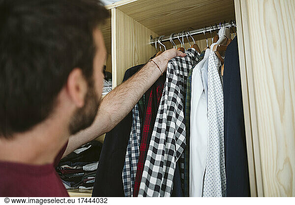 Man removing clothes from closet at home