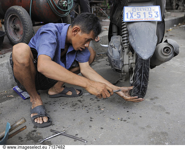 Man repairing a flat tyre of his motorbike