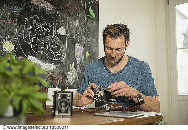 Man repairing antique camera in dining room  Munich  Bavaria  Germany