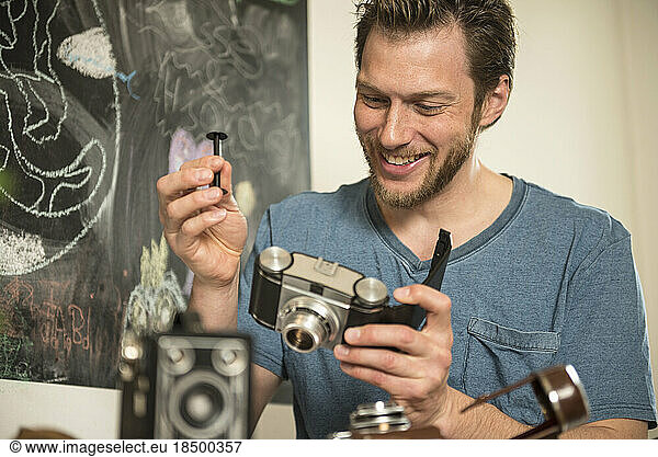 Man repairing antique camera in dining room  Munich  Bavaria  Germany