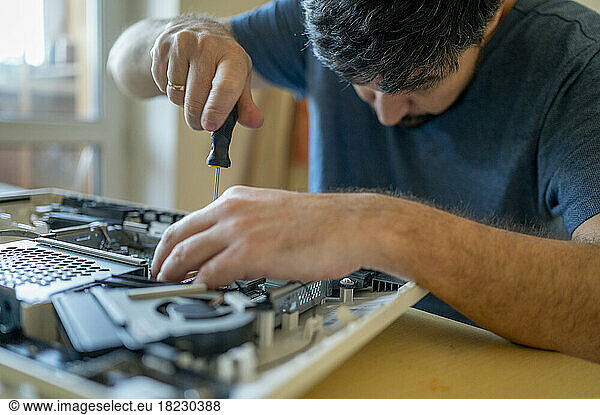 Man repairing computer on table at home