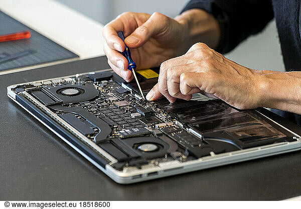 Man repairing laptop with screwdriver