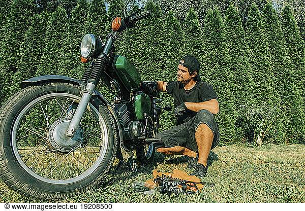Man repairing retro motorbike in garden