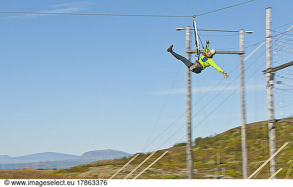 Man riding down a zip-line at high rope access course in Iceland