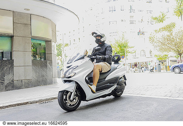 Man riding motor scooter in city