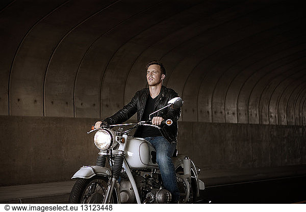 Man riding motorcycle under bridge