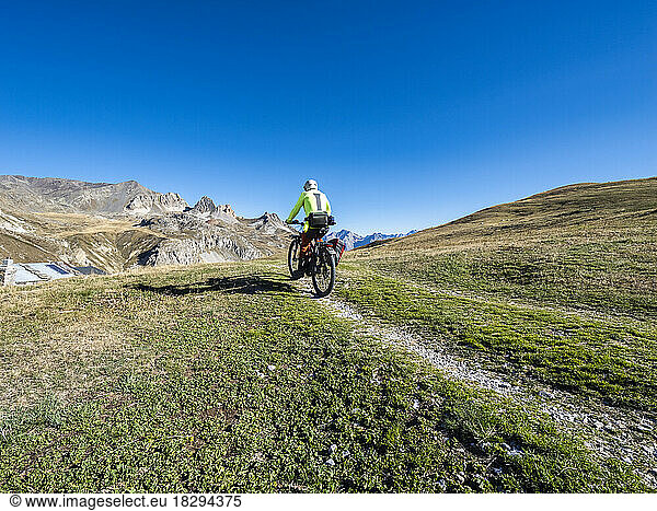 Man riding mountain bike on trail under blue sky  Vanoise National Park  France