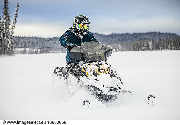 man riding snowmobile on frozen lake.