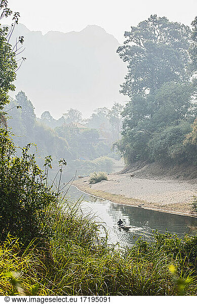 man rowing boat on still river in Laos