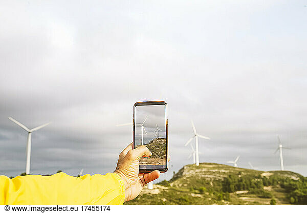 Man's hands take photo of windmills on the mountain