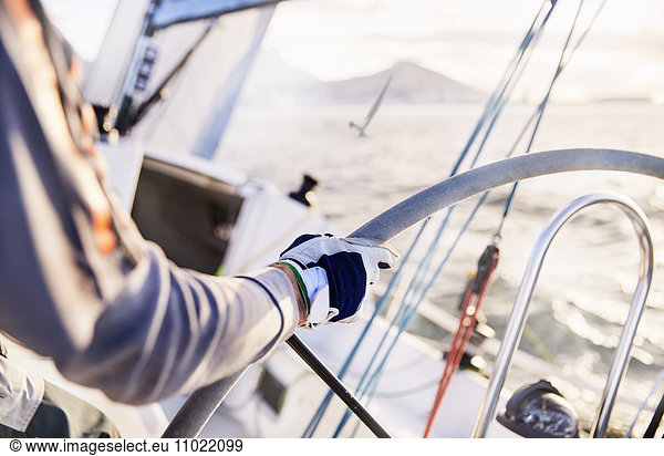 Man sailing steering sailboat at helm