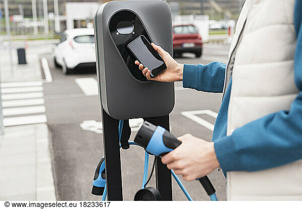 Man scanning and paying through smart phone at charging station