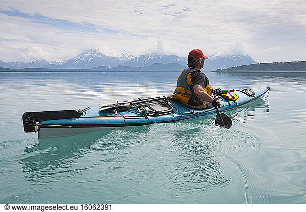 Man sea kayaking calm waters of an inlet in a national park.