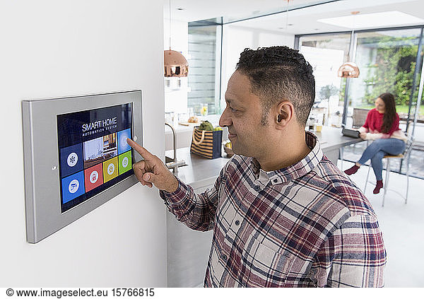 Man setting touch screen smart home alarm