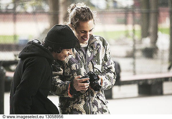 Man showing photographs to friend while standing at skateboard park