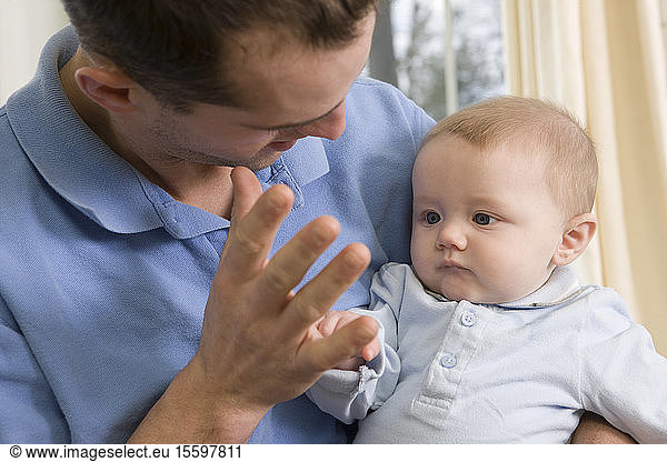 Man signing the word 'Mommy' in American sign language while communicating with his son