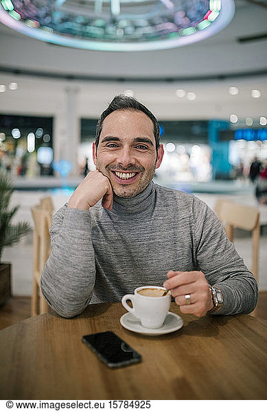 Man sitting in cafeteria  drinking coffee