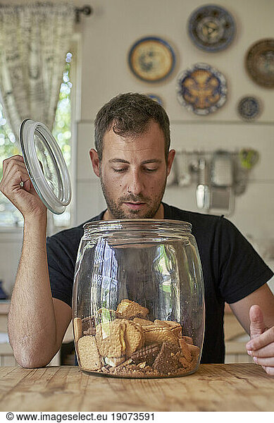 Man sitting in kitchen  looking in cookie jar