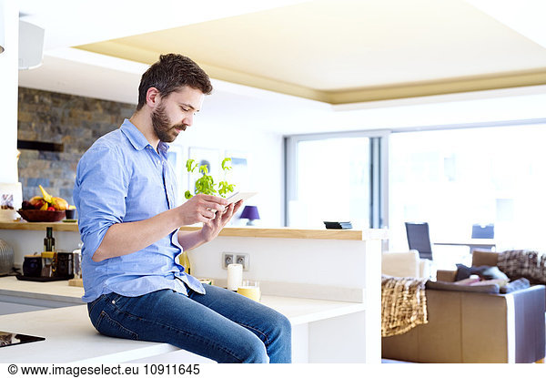 Man sitting in kitchen using smart phone