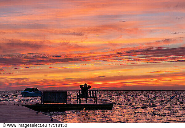 Man sitting on bench enjoying the sunset.