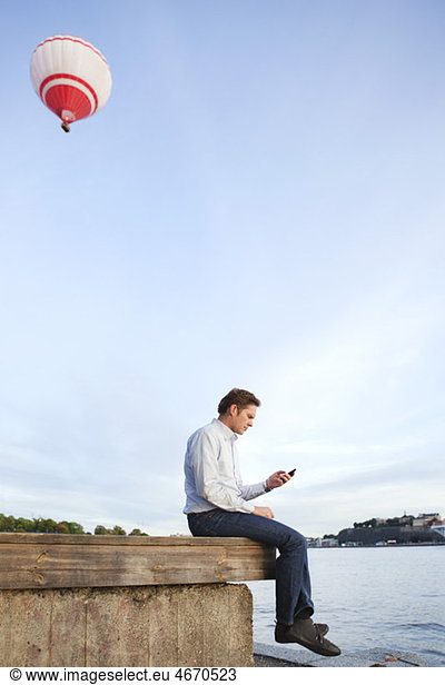 Man sitting on edge with cellphone in his hand