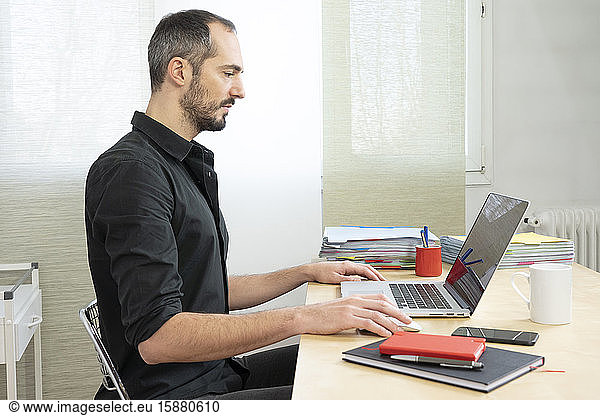 Man sitting upright at his desk.